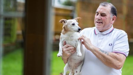 Man holding dog in garden. 