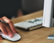 A person using a mouse and computer