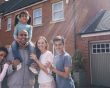 Family stand outside their home